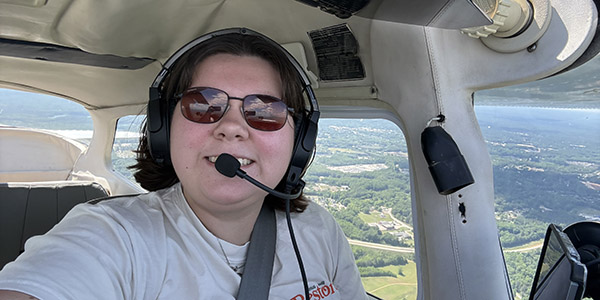 Madelyn Miskell smiling for a photo while flying a plane.